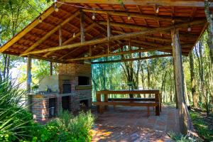 a wooden pavilion with a bench and a fireplace at Caravaggio Container Inn (7 min d Caminho d Pedras) in Farroupilha