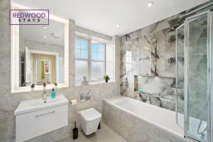 a bathroom with a tub and a toilet and a sink at BRAND NEW! Modern Houses For Contractors & Families with FREE PARKING, FREE WiFi & Netflix By REDWOOD STAYS in Farnborough