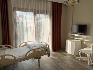 Habitación hospitalaria con cama y ventana en Medila Yaşlı Yaşam ve Bakım Merkezi, en Edremit