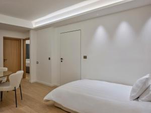 Un dormitorio blanco con una cama y una mesa. en Athenian Loft with Acropolis View, en Atenas