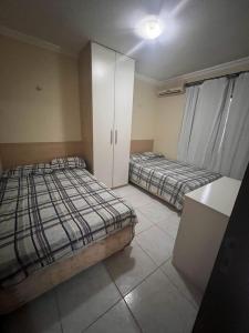 um quarto com 2 camas e um armário branco em Apartamento Ocean View Tabatinga em Nísia Floresta