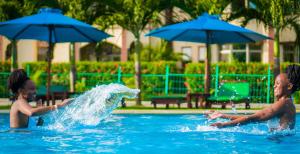 um homem e uma rapariga a brincar numa piscina em Roma Stays - Elegant Apartment at Sunset Paradise with Swimming Pool & Restaurant em Mombasa