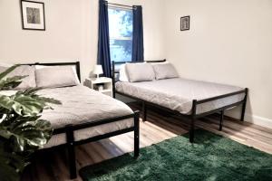 a bedroom with two beds and a green rug at Jay's Cozy Escape - A step from Busch Gardens in Tampa