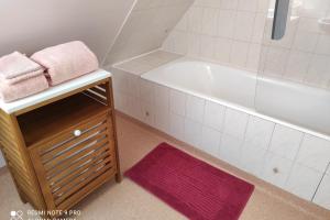 La salle de bains est pourvue d'une baignoire blanche et d'un tapis violet. dans l'établissement Location classée 3 étoiles entre PerrosGuirec et P, à Penvénan