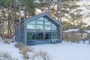 ein kleines Haus mit einem großen Fenster im Schnee in der Unterkunft Strandhus in Travemünde