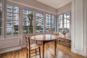 Un comedor con mesa y sillas y ventanas. en Belle villa bauloise à deux pas de la plage, en La Baule