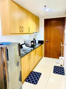 a kitchen with wooden cabinets and a stainless steel refrigerator at D'Hideout in shell residences moa pasay in Manila