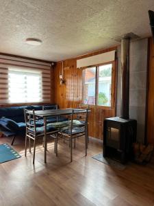 a living room with a table and chairs and a stove at Cabañas Kuyén Austral in Hornopiren