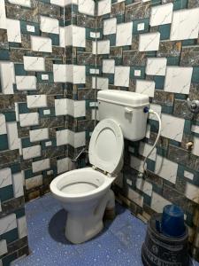 a bathroom with a toilet with a tiled wall at Sunrise Plaza ( ठहरने का उत्तम प्रबंध) in Deoghar