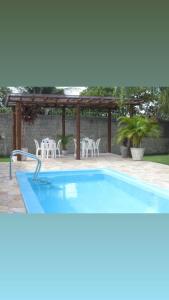 una piscina con sillas y una pérgola en Granja Dona Dora, en Nísia Floresta