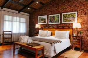 a bedroom with a large bed and a brick wall at El Tránsito Hotel Boutique in Concepción