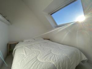 1 dormitorio con cama blanca y ventana en 606 - Appartement à Erquy, à 700m de la plage et des commerces, en Erquy