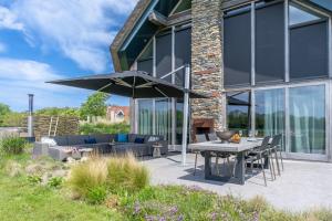 un patio avec une table, des chaises et un parasol dans l'établissement Buytenplaats Villa 191, à De Koog