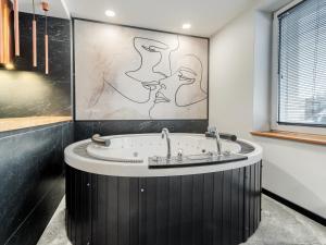 a bathroom with a tub with a painting on the wall at JACUZZI A&J APARTS GDYNIA in Gdynia