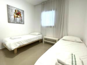 a small room with two beds and a window at Stylish 3BR Golf Residence Eilat in Eilat