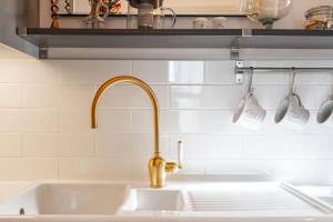 um lavatório de cozinha com uma torneira de ouro e três copos de medida em Bijou apartment in the heart of Melrose em Melrose