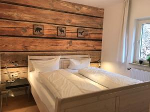 um quarto com uma cama branca e uma parede de madeira em Platell Ferienhausverwaltung Sankt Andreasberg em Sankt Andreasberg