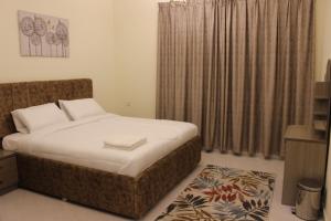 a bedroom with a large bed and a rug at أمجاد للشقق الفندقية in Al Ḩuwayl