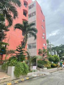 a red building with palm trees in front of it at The Bachelor's Suite at Mactan Airport in Pusok