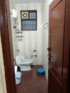 a small bathroom with a toilet and a window at Shri Achyutam Villas in Vrindāvan