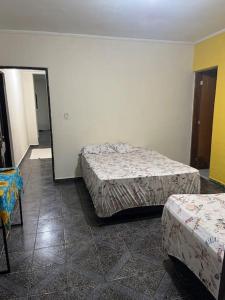 Cette chambre comprend 2 lits et un miroir. dans l'établissement Chácara Rei Davi - Várzea, à Várzea Paulista