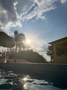 una piscina con el sol en el cielo en Chácara Rei Davi - Várzea, en Várzea Paulista
