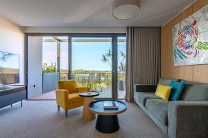 una sala de estar con un sofá y una mesa en Les Jardins du Cèdre, Boutique hôtel & gastronomie, en Port-Vendres