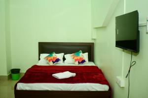 JM Suites في Tezpur: غرفة نوم مع سرير وتلفزيون بشاشة مسطحة