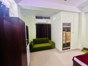 JM Suites في Tezpur: غرفة معيشة مع كرسي أخضر في غرفة