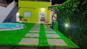 a backyard with a green wall and a swimming pool at Casa p/ temporada, praia guaibim in Guaibim