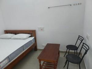 a bedroom with a bed and two chairs and a table at Hill house in Tiruvannāmalai