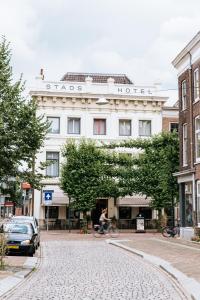 un hombre montando una bicicleta delante de un hotel en Stadshotel Steegoversloot, en Dordrecht