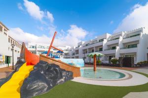 a playground in front of a large apartment building at Apartamentos Galeon Playa in Costa Teguise