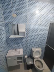La salle de bains est pourvue de carrelage bleu, de toilettes et d'un lavabo. dans l'établissement Kitnets em Caraguatatuba, à Caraguatatuba
