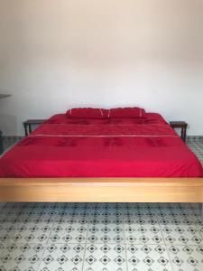 Una cama con un edredón rojo encima. en Palm Villas Estate, en Bijilo