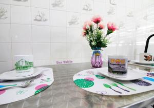 a table with two plates and a vase of flowers at H2H - Bintang49 Vacation House in Ipoh +18 photos