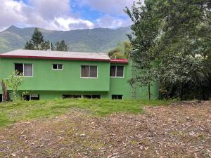 una casa verde con techo rojo en un campo en Villa Don Manuel en Villa Altagracia