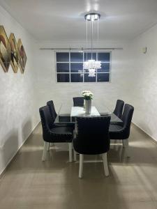 a dining room table with black chairs and a chandelier at Residencial Joyas D’ Luxe III A3 in Santiago de los Caballeros