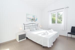1 dormitorio blanco con 1 cama y 1 silla en Villa Macarella by Sonne Villas, en Cala Galdana
