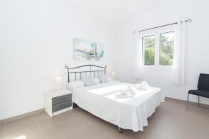 a white bedroom with a bed and a chair at Villa Macarella by Sonne Villas in Cala Galdana +96 photos