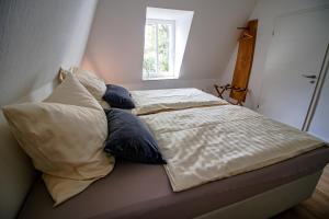 een slaapkamer met een bed met kussens en een raam bij Harzträume No1 & 2 Doppelwohnung in Wernigerode