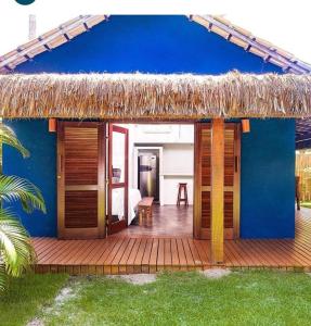 une maison bleue avec une terrasse au toit de chaume dans l'établissement Casa Bora Lá, à Caraíva