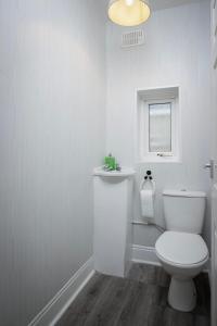 een witte badkamer met een toilet en een raam bij Beautiful Family Home in Blackpool for you in Blackpool