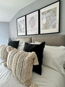 a white bed with four framed pictures above it at Guest Homes - Rice Lane Retreat in Walton on the Hill