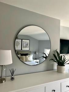 a mirror on a white wall in a bedroom at Guest Homes - Rice Lane Retreat in Walton on the Hill