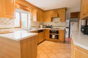 a kitchen with wooden cabinets and white counter tops at Traditional English country 4 bed cottage near Chester - For 7 people in Pulford