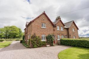 a large brick house with a gravel driveway at Traditional English country 4 bed cottage near Chester - For 7 people in Pulford