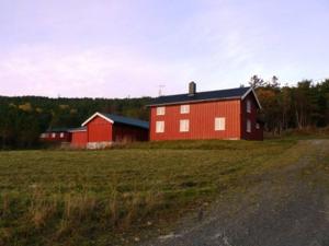 un granero rojo sentado en un campo junto a una carretera en Edvinstua Solbakken Feriehus, en Fevåg