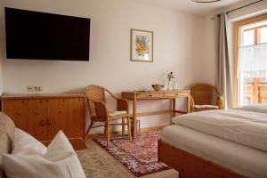 Schlafzimmer mit einem Bett, einem Schreibtisch und einem TV in der Unterkunft Chesa Platina in Schruns-Tschagguns