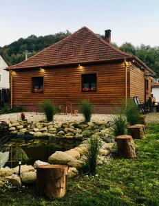 a log cabin with a pond in front of a house at Mátrai pincés udvar in Mátramindszent